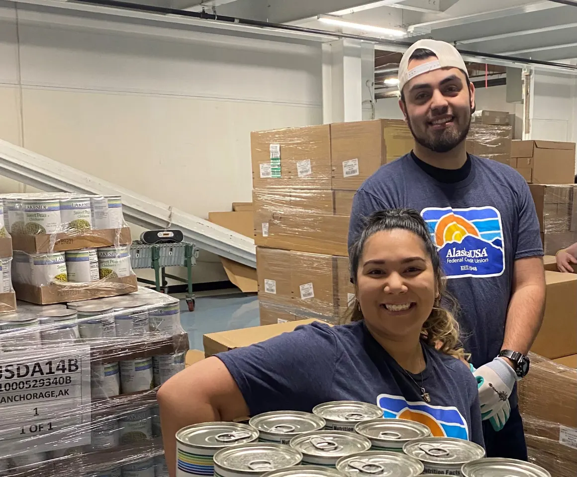 Two smiling Alaska USA volunteers at a food bank warehouse